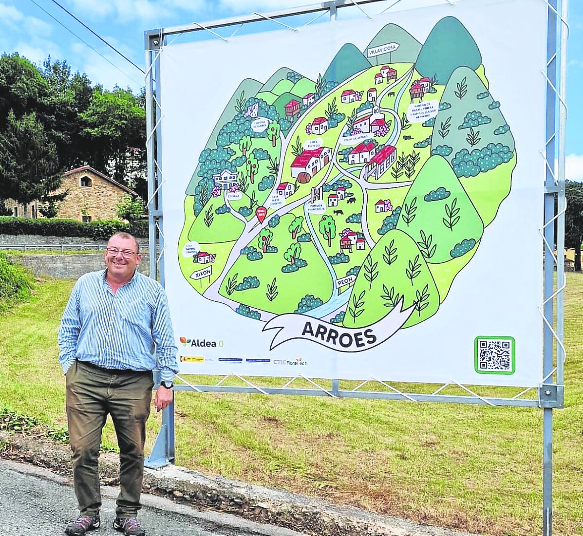 Ricardo Riera en Arroes junto a un cartel promocional de la parroquia premiada.