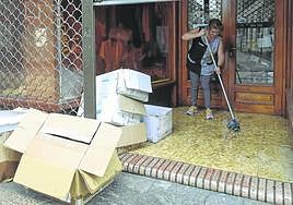 Tienda El Chico. Esther López friega la entrada de su negocio inundado por la lluvia que cayó con intensidad durante la noche, y saca las cajas mojadas.