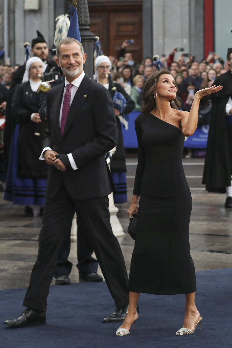 La Reina Letizia ha optado por un favorecedor y ceñido vestido negro de escote asimétrico de Carolina Herrera que le dejaba un hombro al descubierto. 