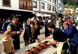 Varias familias prueban los trece potes participantes en la XX fiesta del potaje de Navelgas.