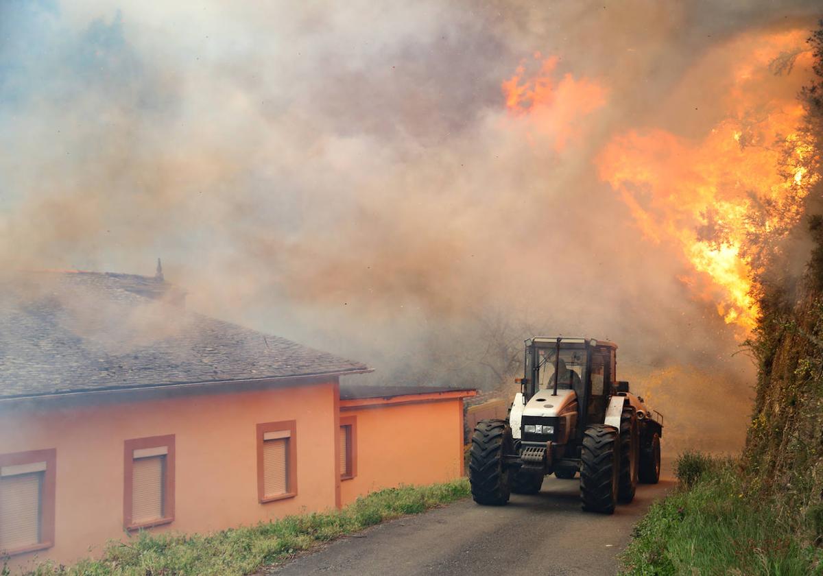 Un tractor rodeado por el fuego declarado el pasado mes de febrero en Ovienes, en Valdés.