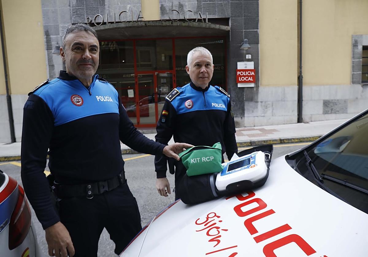Los agentes de la Policía Local Carmona y Francisco muestran el desfibrilador delante de la jefatura de la calle San José.