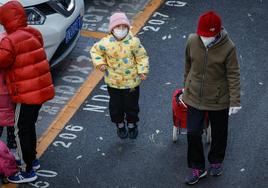 Un niño y un adulto llevan mascarilla a la salida de la escuela en Pekín, China.