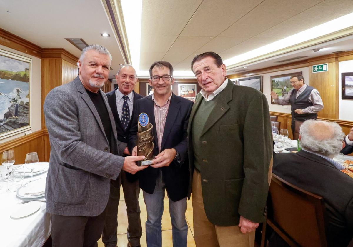 Belarmino Feito entrega la escultura a Ángel González, en presencia de Fernando de la Hoz y Adolfo García.