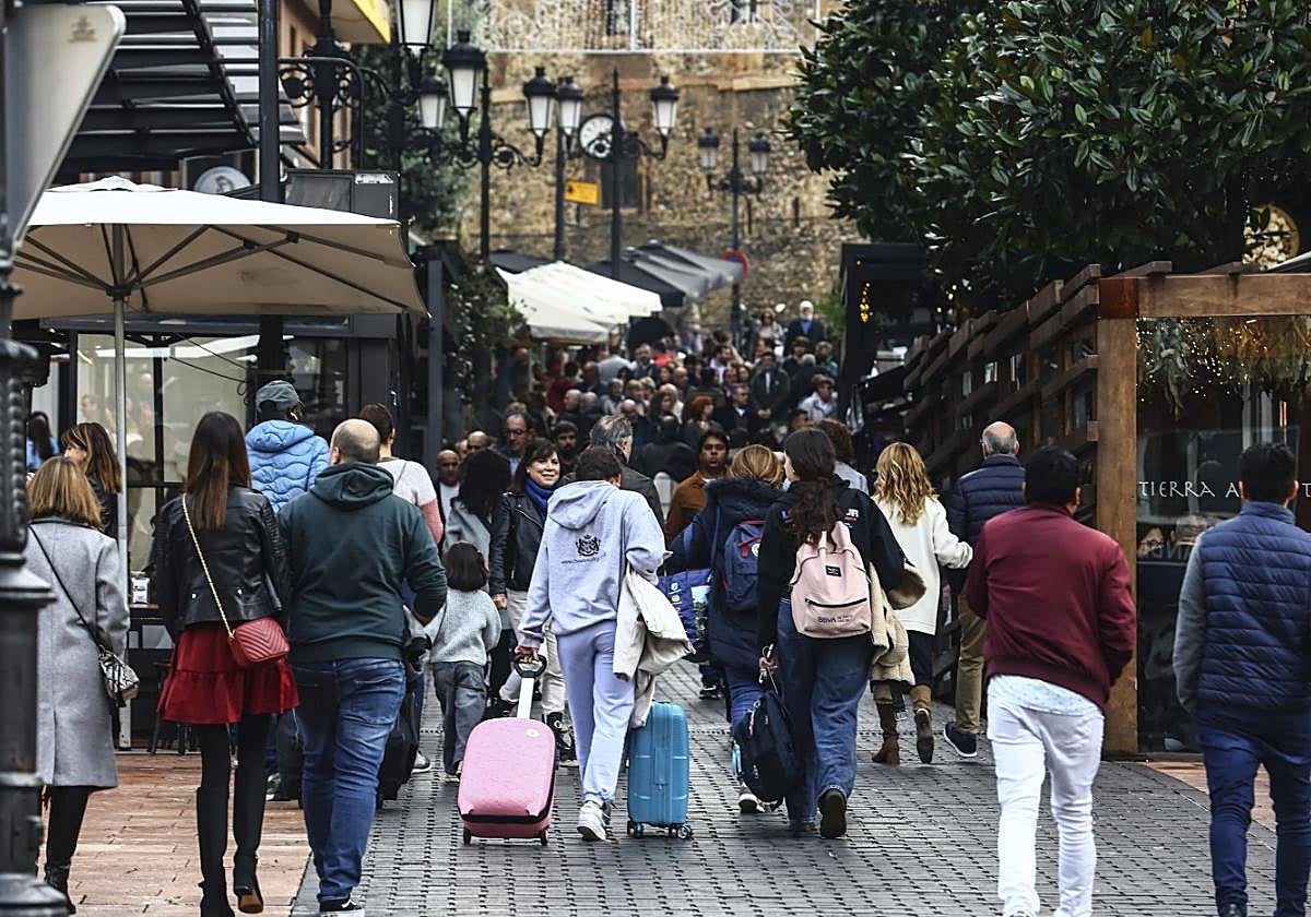 Dos jóvenes, con sus maletas, suben por una abarrotada calle Gascona.