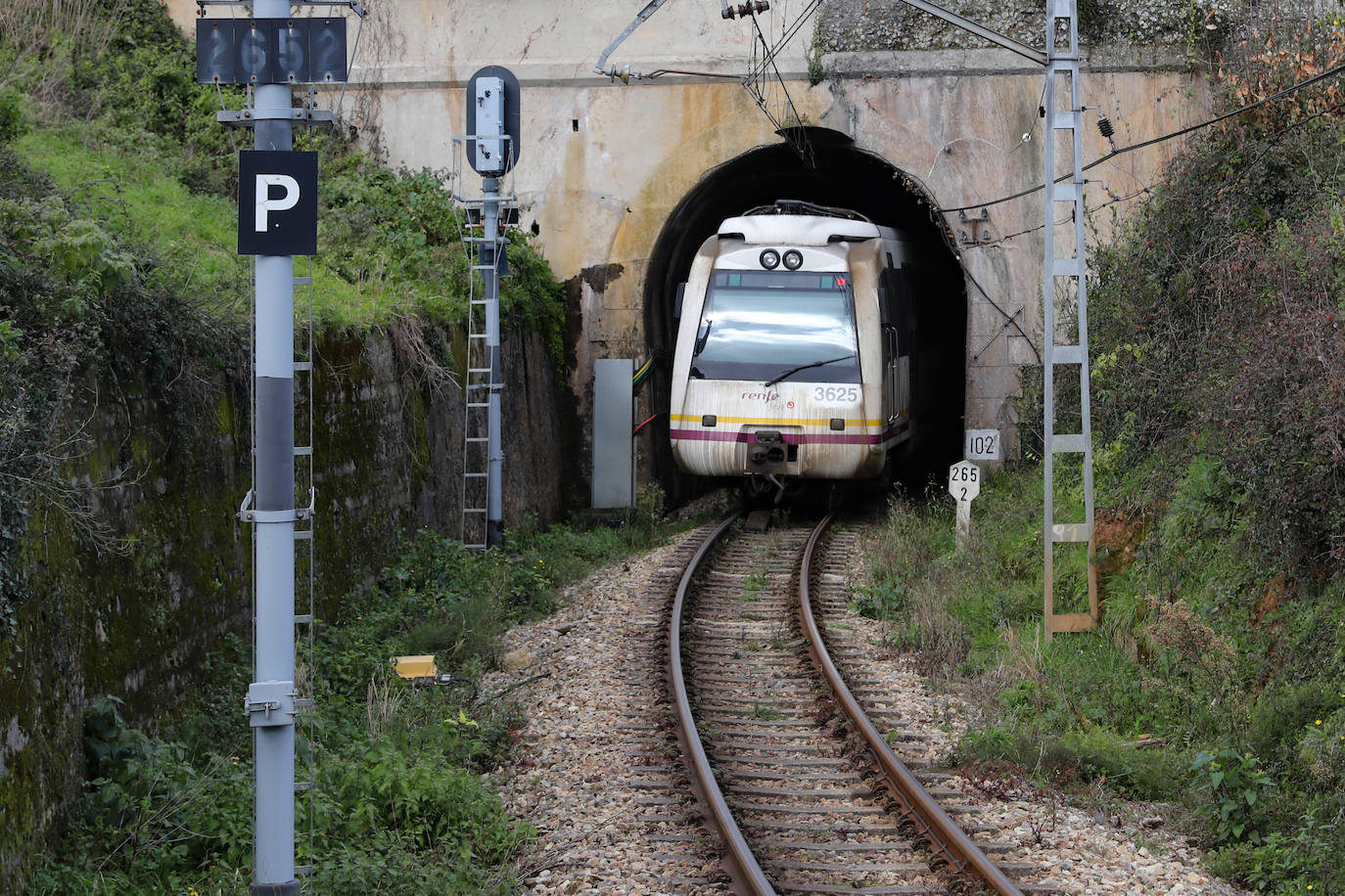 Un tren de FEVE circula cerca de Pravia, en uno de los tramos con túneles más estrecho de Asturias.