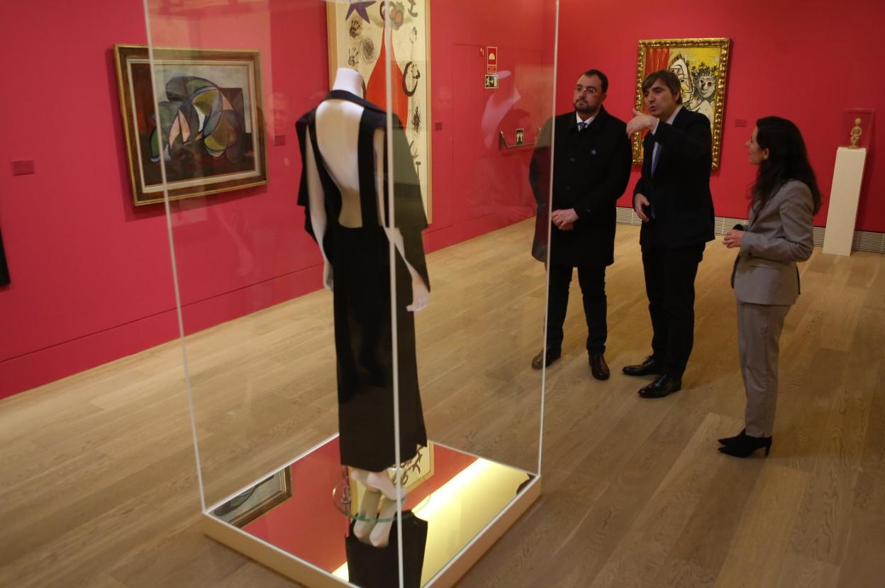 Adrián Barbón, ante el vestido de Saint Laurent con Alfonso Palacio, director del Bellas Artes, y Sara Moro, responsable de Comunicación de la pinacoteca. 