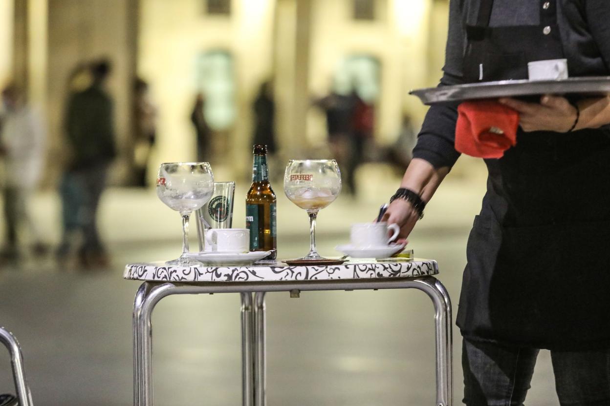 Un camarero recoge la mesa de una terraza. 