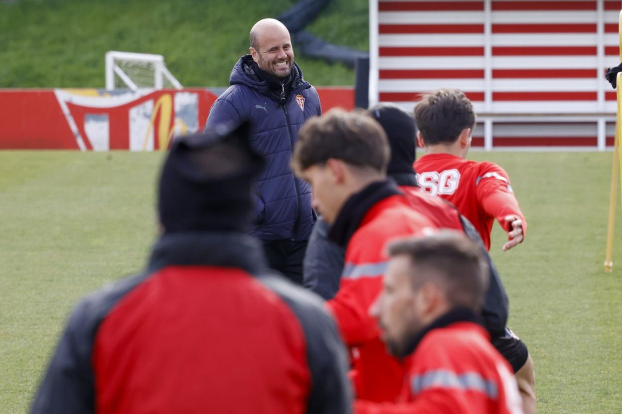 El entrenador del Sporting, Miguel Ángel Ramírez, sonriendo en Mareo durante el calentamiento de sus futbolistas, con varios jugadores en primer plano. 