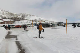 Varias personas preparan sus equipos para la nieve en el aparcamiento de la estación de Fuentes de Invierno, que estaba lleno.
