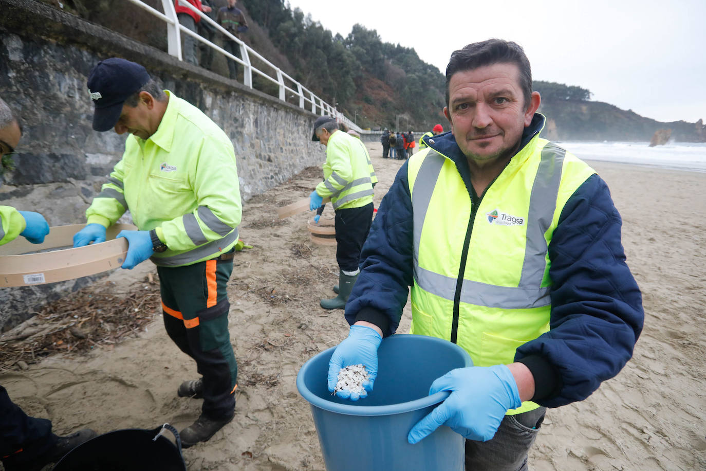 Operarios retiran los pellets o bolitas para fabricar plástico que aparecen en las playas de Asturias, tras la caída de un contenedor de un barco el pasado diciembre, esta mañana en la playa asturiana del Aguilar.
