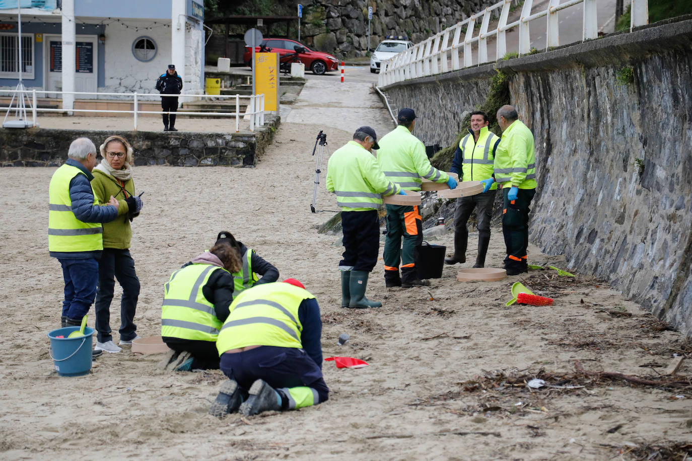 Operarios retiran los pellets o bolitas para fabricar plástico que aparecen en las playas de Asturias, tras la caída de un contenedor de un barco el pasado diciembre, esta mañana en la playa asturiana del Aguilar.