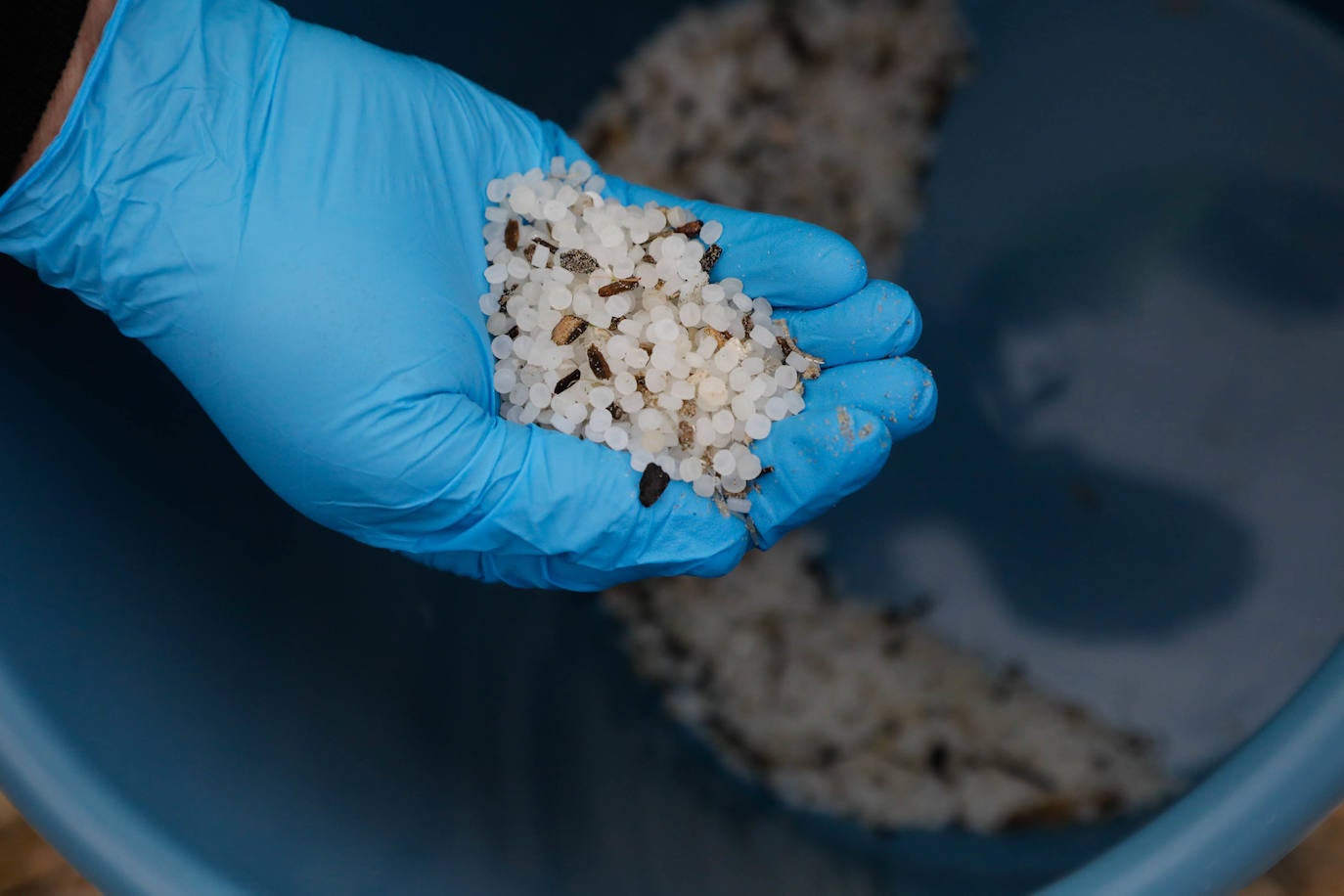 Operarios retiran los pellets o bolitas para fabricar plástico que aparecen en las playas de Asturias, tras la caída de un contenedor de un barco el pasado diciembre, esta mañana en la playa asturiana del Aguilar.