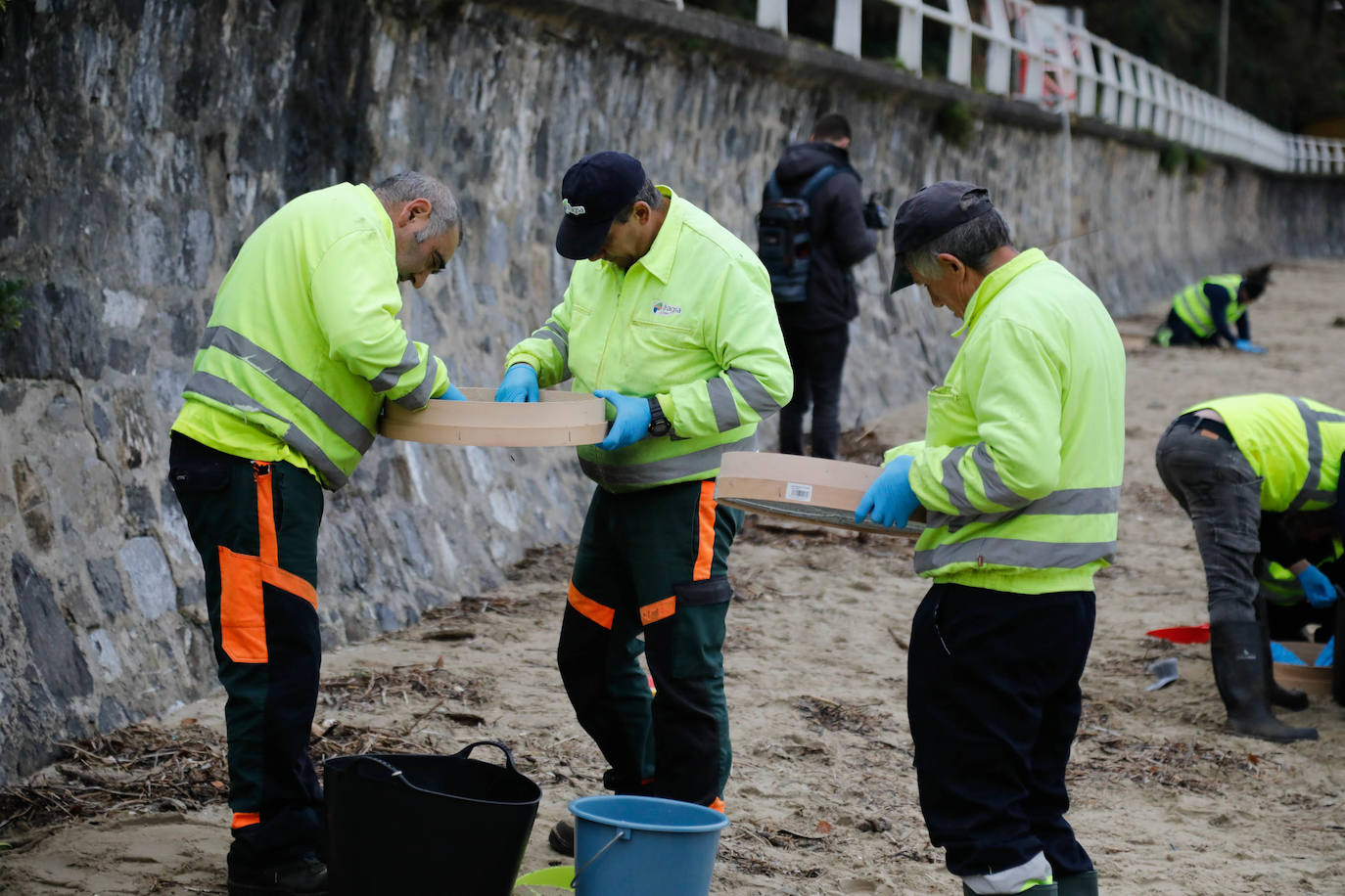 Operarios retiran los pellets o bolitas para fabricar plástico que aparecen en las playas de Asturias, tras la caída de un contenedor de un barco el pasado diciembre, esta mañana en la playa asturiana del Aguilar.