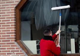 Un trabajador limpia el cristal de un establecimiento hostelero.