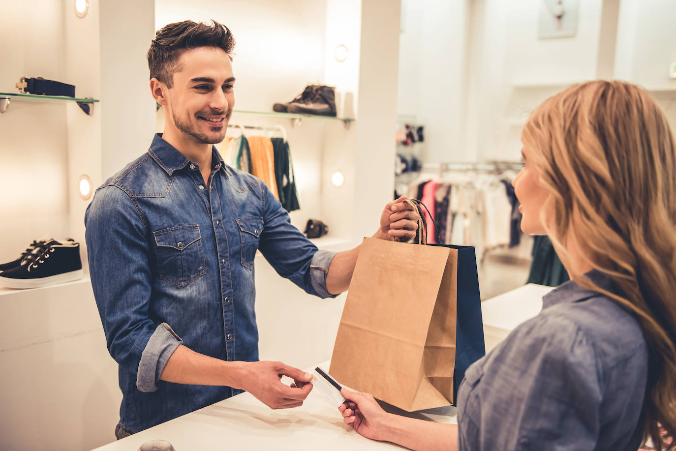 Una clienta le entrega su tarjeta de crédito al dependiente para pagar su compra.