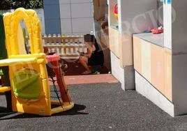 Fotografía incluida en la denuncia, en la que se puede ver a un niño en el alféizar de una ventana del patio y a la profesora con el móvil.