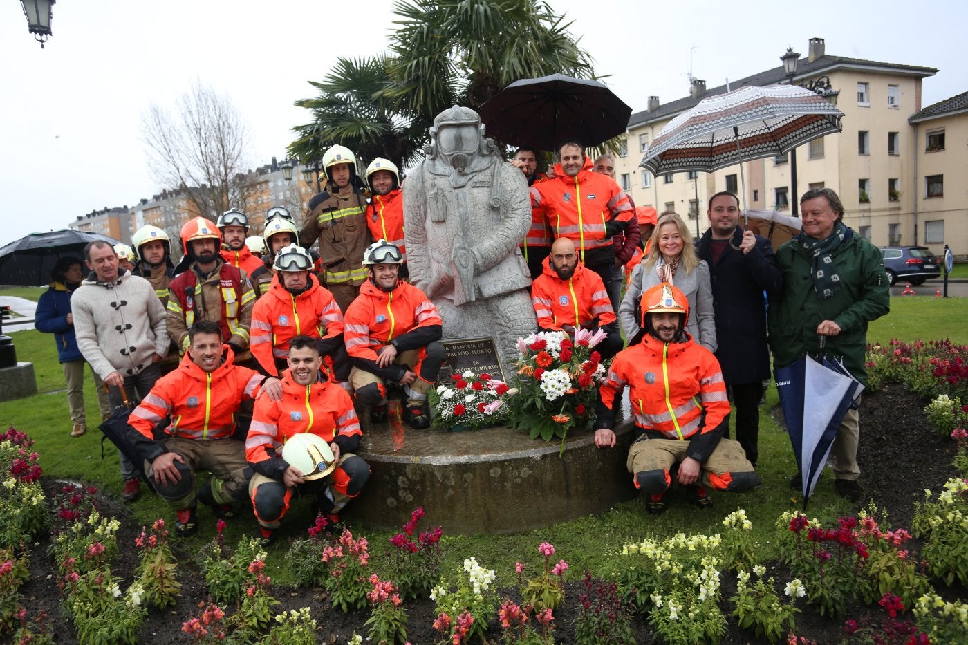 Los bomberos de Oviedo, con la familia de Eloy Palacio y el edil de Seguridad Ciudadana ante la estatua que recuerda al fallecido.
