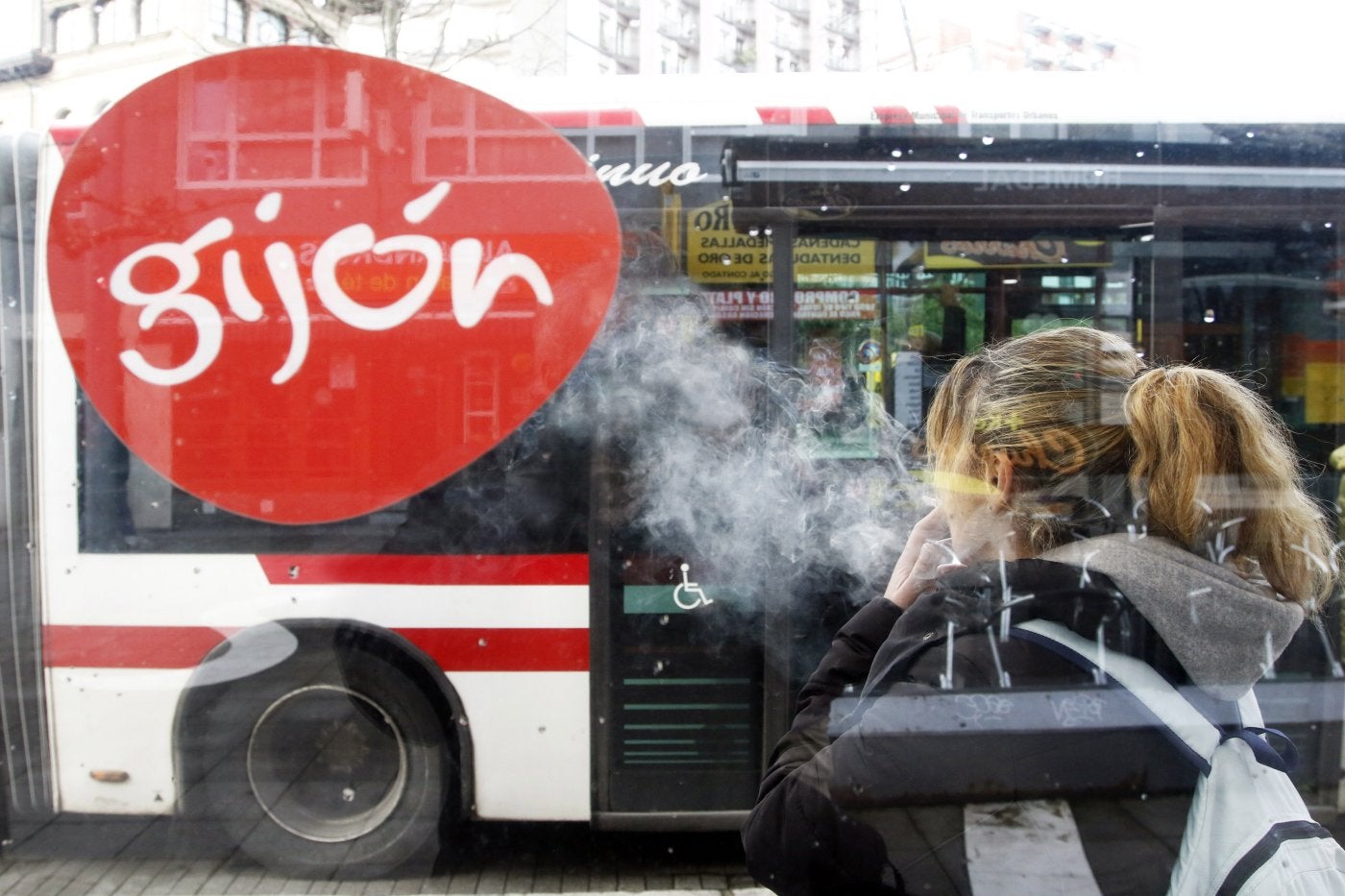 Una joven fuma bajo una marquesina, donde se estudia prohibirlo.