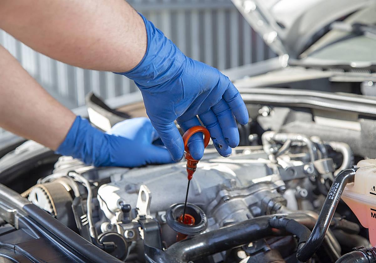Un mecánico comprueba el aceite de un coche.