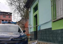 Un vehículo de la Policía Nacional delante de las viviendas en cuya huerta aparecieron las bolsas con restos humanos, en La Felguera.