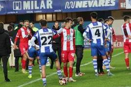 Los jugadores del Real Avilés, resignados al final del partido, con varios miembros del club dialogando con los colegiados.
