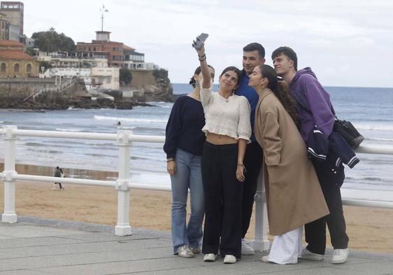 Un grupo de jóvenes se hace un selfi en el paseo del Muro de Gijón.