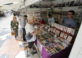 Varios clientes miran los puestos de la Feria del Libro de Gijón y se interesan por algunos ejemplares.
