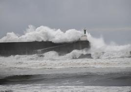 El faro de la barra de San Esteban, ayer, batido por las olas, con la rampa por la que subió el ciudadano inglés antes de ser arrastrado.