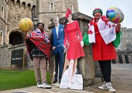 Dos mujeres posan junto a unas imágenes de Kate Middleton y el Rey Carlos III frente al Castillo de Windsor.