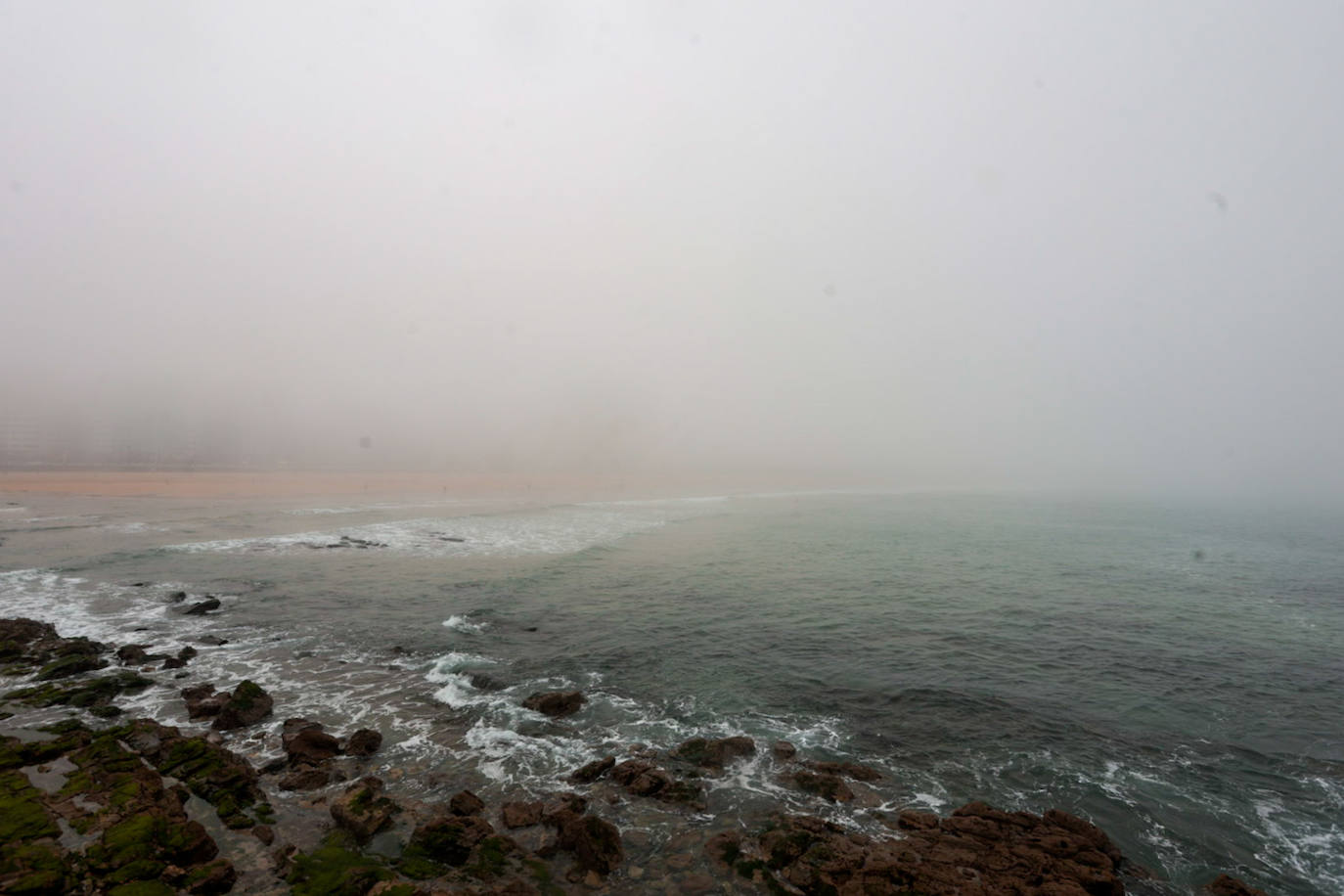 Gijón pasa de un día de sol y playa a una mañana siguiente de niebla