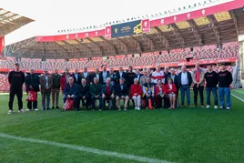 Foto de familia de los nuevos socios de honor del Sporting, con los representantes de la plantilla y del club, en el césped de El Molinón.