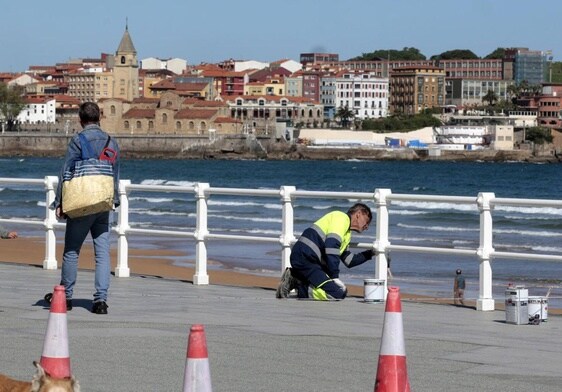 Operarios pintan la barandilla de la playa de San Lorenzo esta mañana.