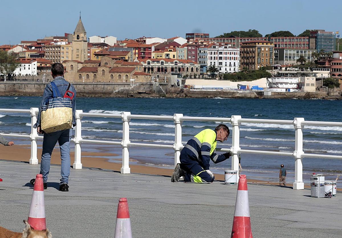 Operarios pintan la barandilla de la playa de San Lorenzo esta mañana.