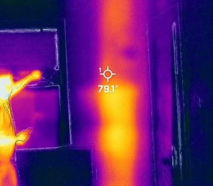Una imagen con cámara térmica en la que se ve que hay algo que emite calor tras la pared.