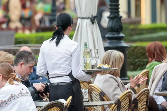 Una camarera atiende a los clientes de una terraza, en Gijón.