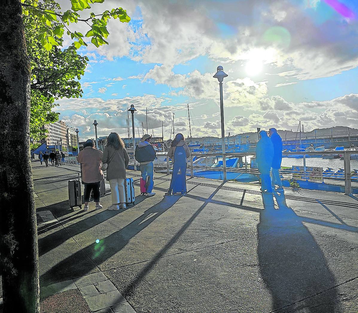Un grupo de jóvenes turistas contempla la puesta del sol desde el paseo de Fomento de Gijón.