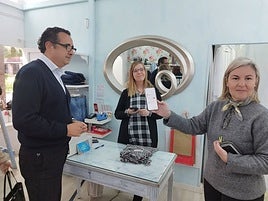 De izquierda a derecha, el director general de Comercio, Julio González Zapico, y la propietaria de la tiendina de Nu en Langreo, Nuria Álvarez, con una clienta que ya había descargado los bonos descuento en su teléfono móvil.