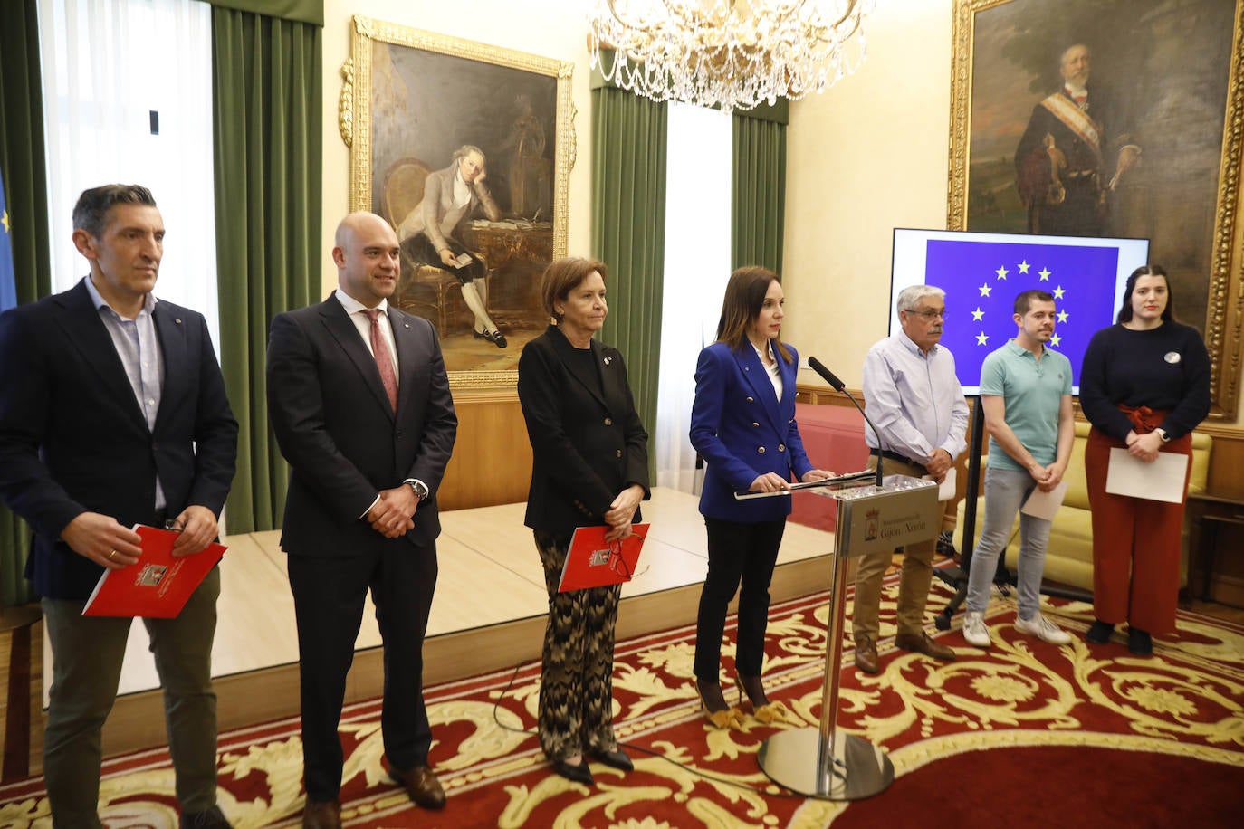 La alcaldesa, Carmen Moriyón, junto a los representantes de los grupos políticos municipales y Laura González, responsable de la Oficina de Relaciones Internacionales en el atril.