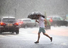 Un joven, bajo las lluvias en Oviedo.