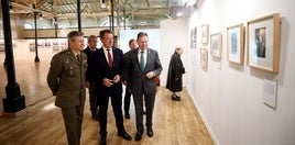 El teniente coronel Jesús rueda, el director general de Santa Bárbara, Juan Escriña, y el alcalde, Alfredo Canteli, visitan las exposición en Trascorrales.