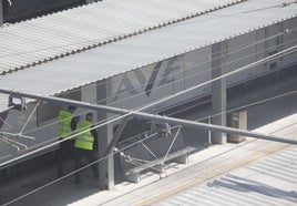 Dos hombres, en la estación de tren gijonesa con el cuerpo del fallecido.