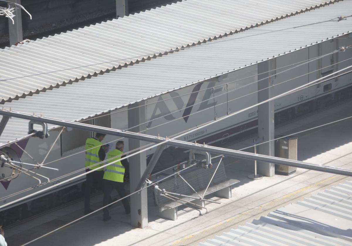 Dos hombres, en la estación de tren gijonesa con el cuerpo del fallecido.