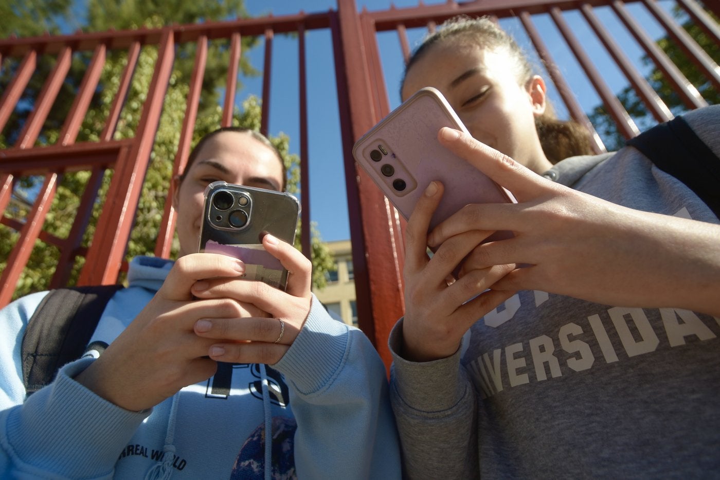 Dos adolescentes utilizan el teléfono móvil en las inmediaciones de su instituto.