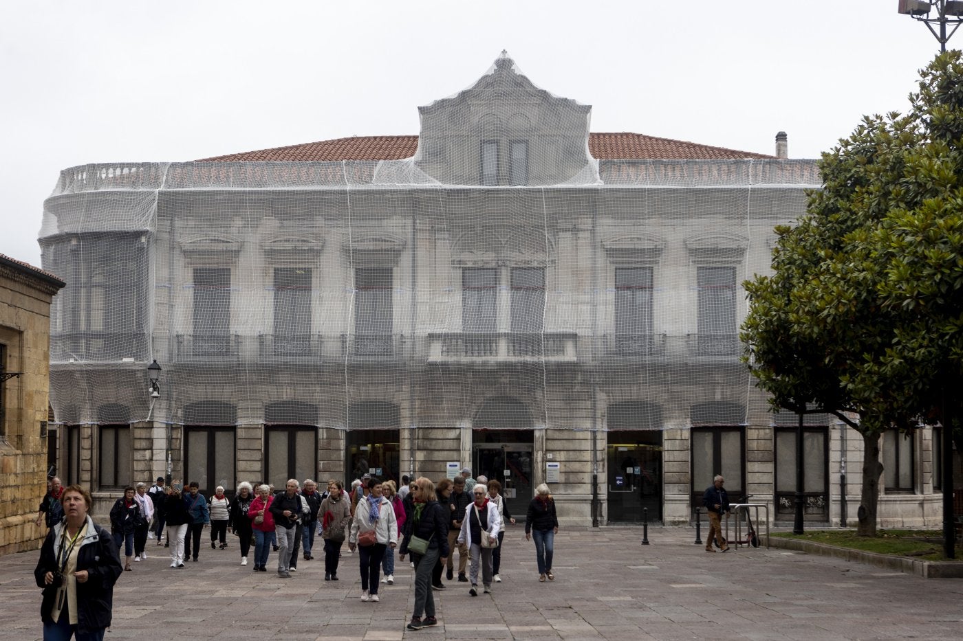 Un grupo de personas pasea por la Corrada del Obispo, ante la fachada del Conservatorio, protegida con una malla.