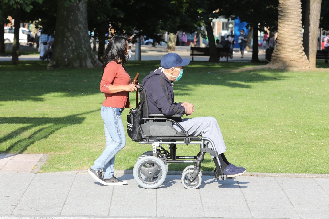 Una joven ayuda a un usuario de silla de ruedas.