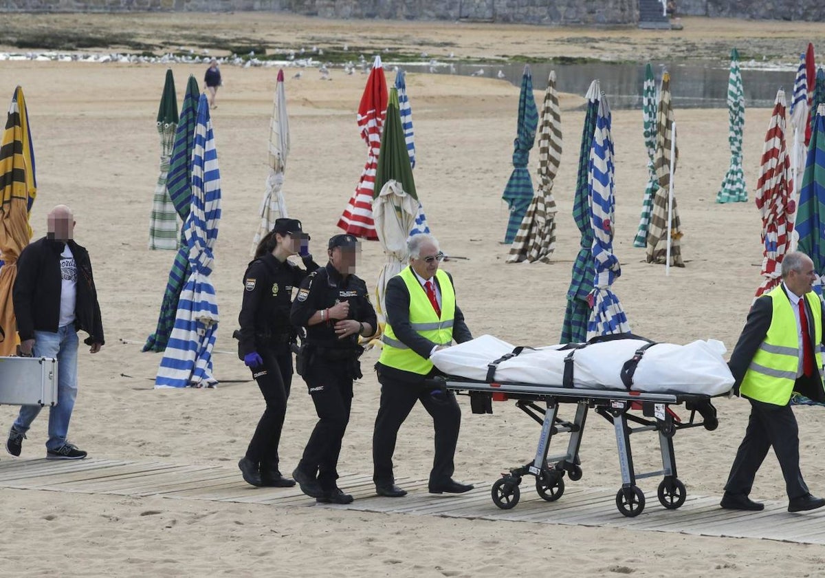 Agentes de la Policía Nacional y los servicios funerarios trasladan el cadáver.