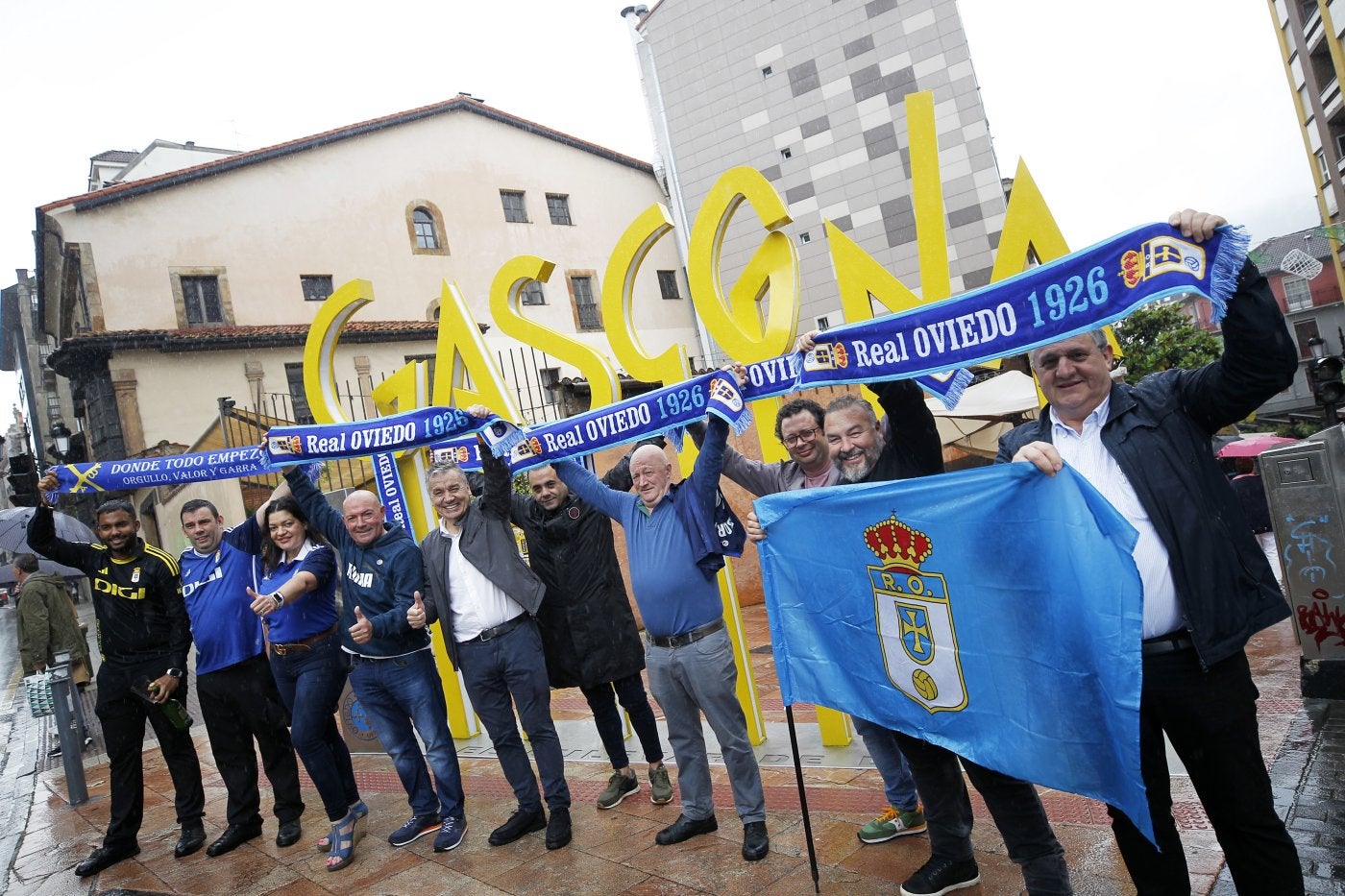 Los chigresos de Gascona animan al equipo bajo la lluvia desde las letronas de la calle mientras uno de sus camareros escancia un culín por el ascenso a Primera.