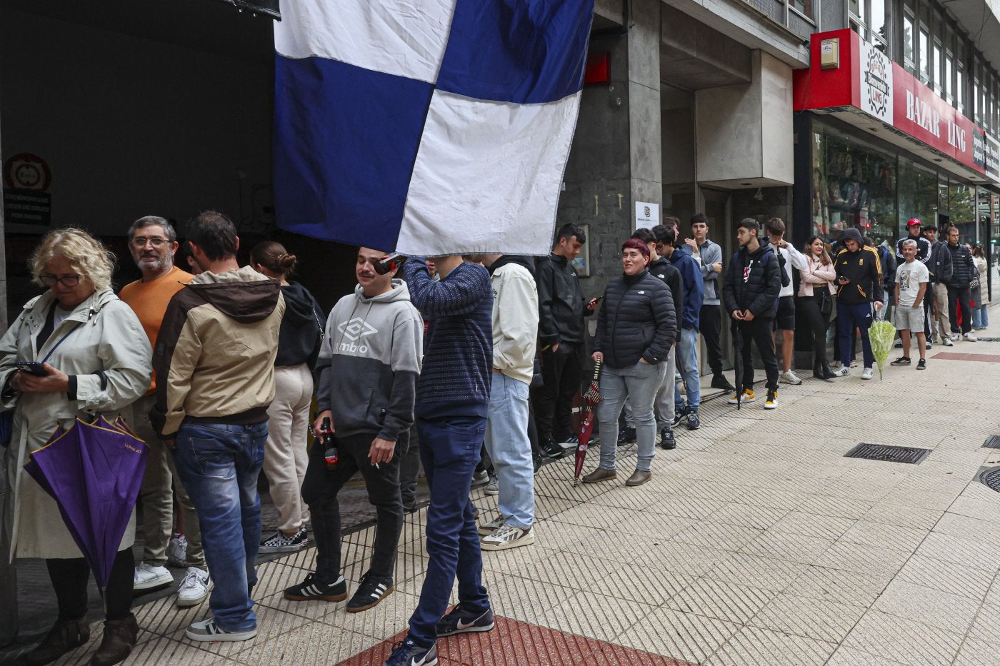 Aficionados del Real Oviedo esperando para conseguir sus boletos para viajar a Barcelona con el equipo.