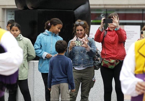 Un grupo de turistas, en la plaza de la Escandalera, observan la actuación de los gaiteros del Folclore en la Calle.